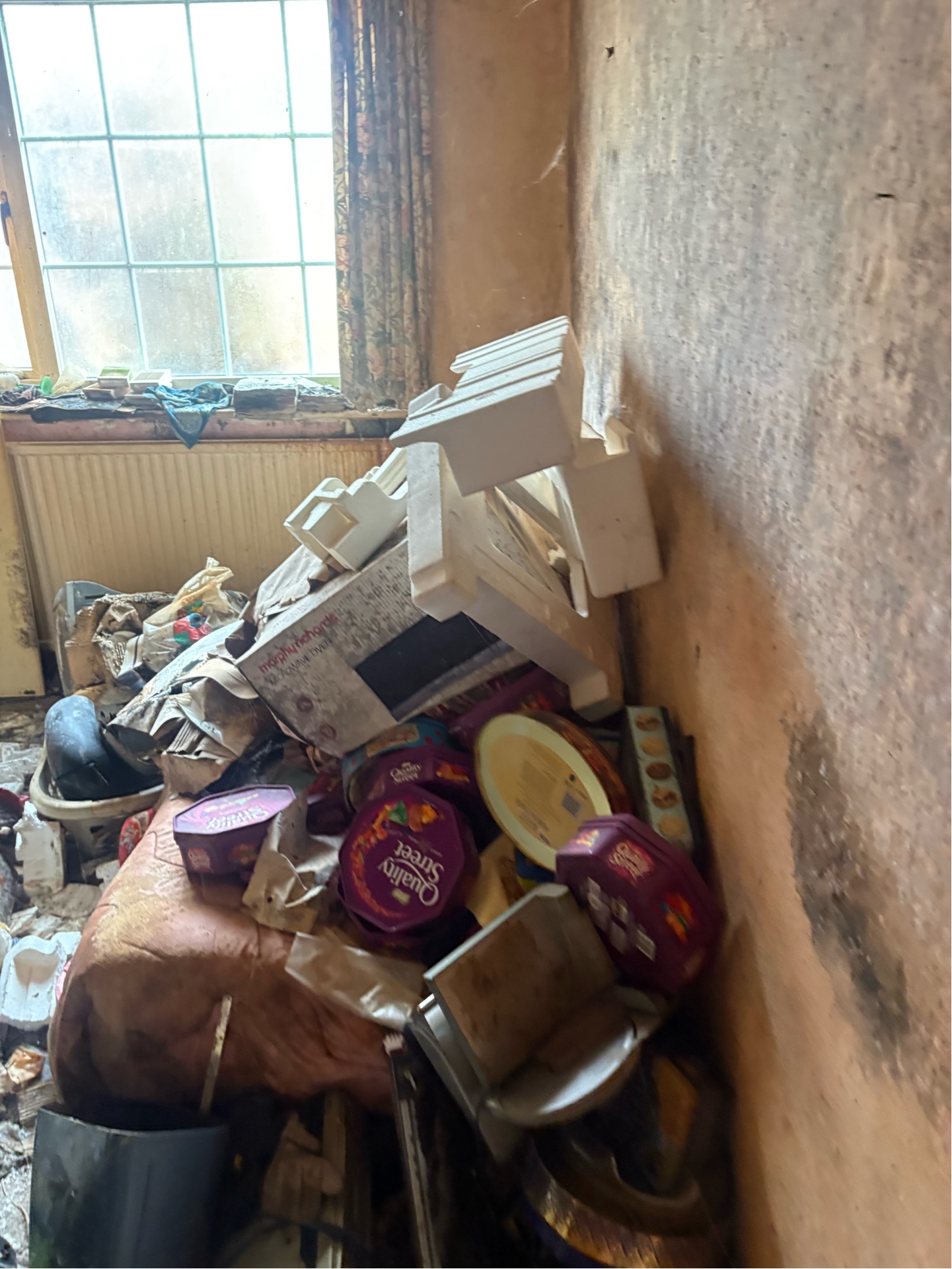 Property clearance — hoarded room, Quality Street tins and packed debris